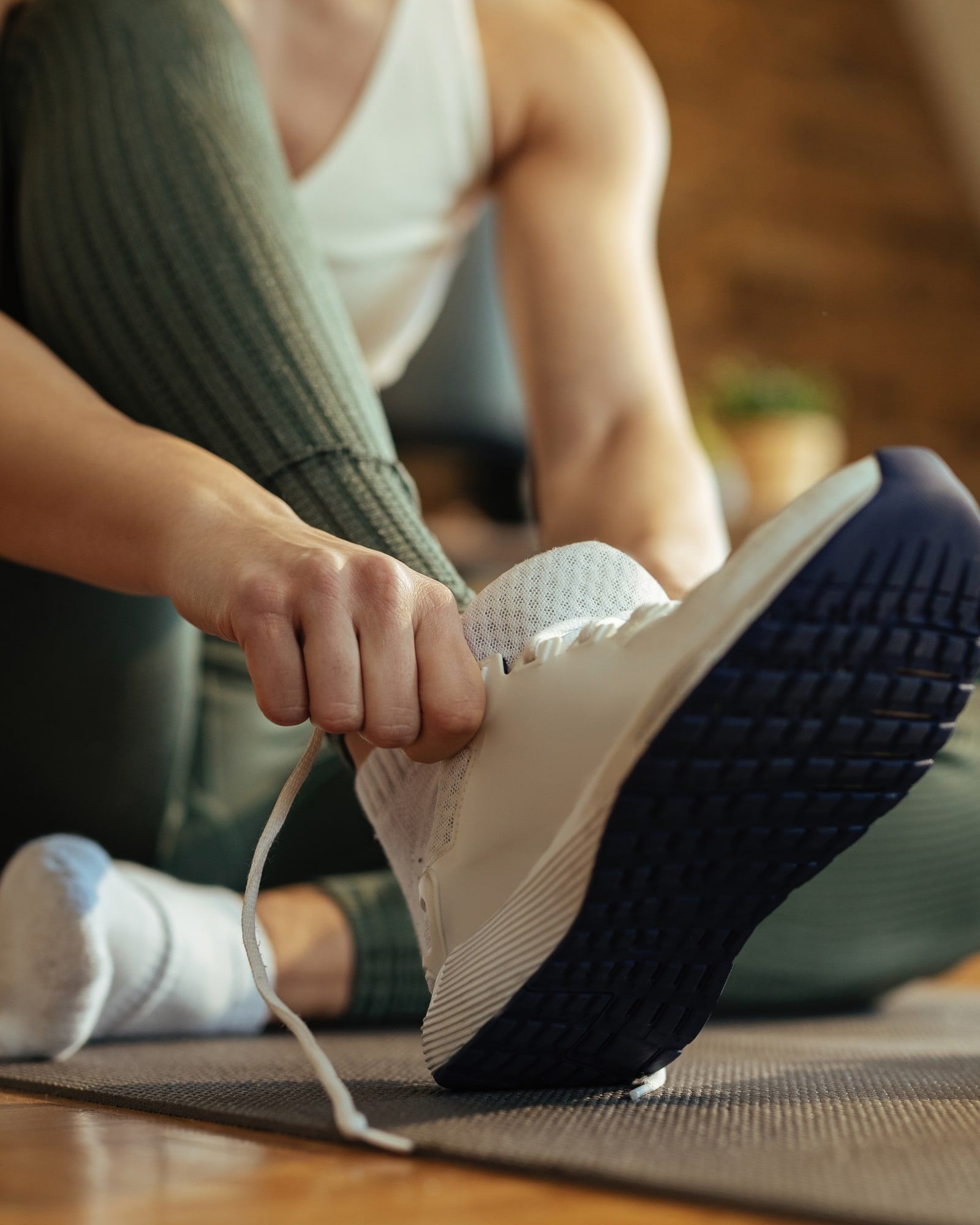 Someone sitting on the floor at home, pulling on a running shoe